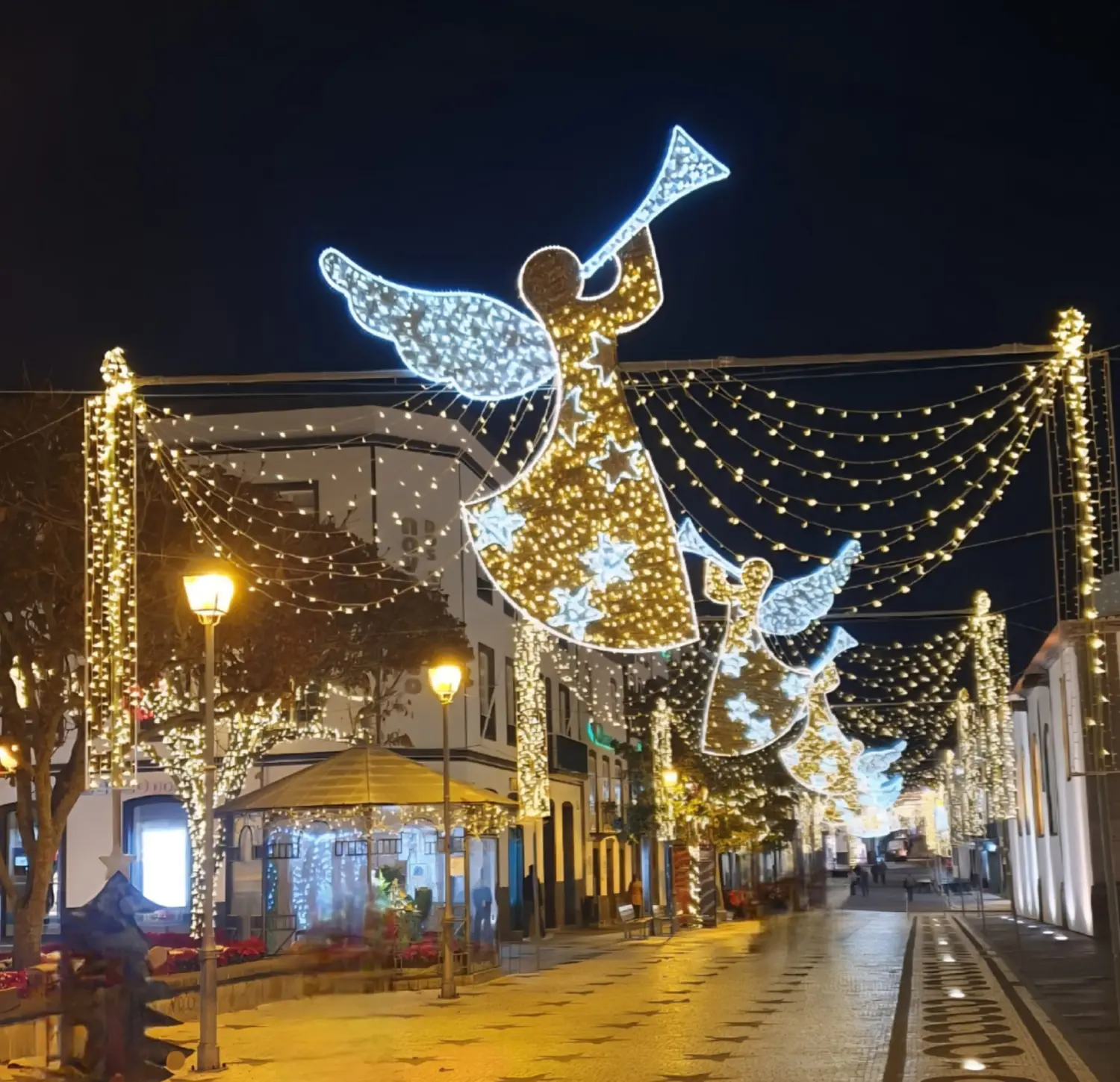 Villa Magia Verde – eine mit Weihnachtsbeleuchtung geschmückte Straße, Engel figuren, die auf der anderen Straßenseite und auf Bäumen Trompete spielen